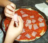 Poniendo trocitos de jam�n York en la pizza